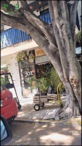 A red car is parked in front of a store with a sign that says "30% off."