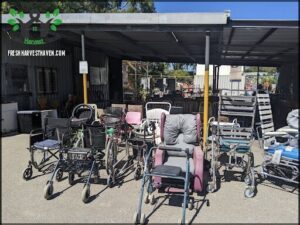 A row of wheelchairs are parked under a metal roof.