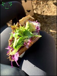 A sandwich with lettuce and purple cabbage on a plate.
