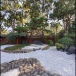 A serene garden with a tree, rocks, and a path.