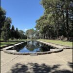 A serene pond surrounded by trees and a stone wall.