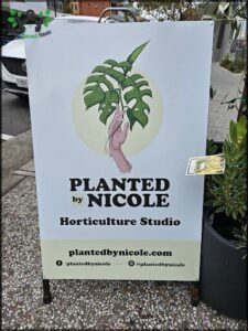 A sign advertising a plant nursery is displayed in front of a building.