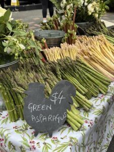 A sign advertising green asparagus sits on a table.