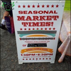 A sign advertising seasonal market times is displayed on a table.