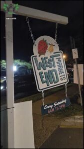 A sign for West End Market hangs from a pole.