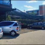A silver car is parked under a large umbrella, providing shade and protection from the elements.