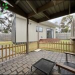 A small house with a wooden deck and a patio set.