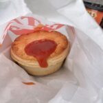 A small pastry with a red sauce drizzled over it.