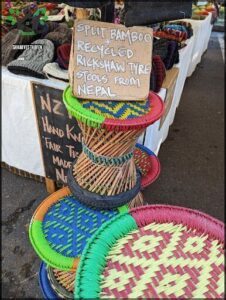 A stack of colorful woven baskets and stools are displayed for sale.