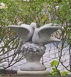 A statue of a dove with a wreath on its chest.
