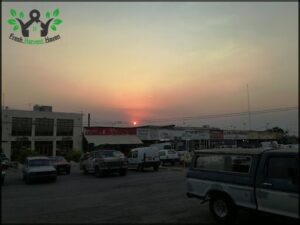A sunset over a parking lot filled with cars.