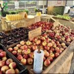 A table full of apples and other fruits, with a price sign on the table.