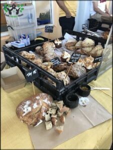 A table full of baked goods, including bread, muffins, and cakes, is displayed in a bakery.