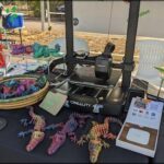A table full of colorful crocodile toys and a 3D printer.