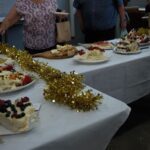 A table full of desserts, including cakes and pies, is adorned with gold and white decorations.