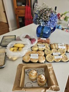 A table full of food, including a variety of pastries and a vase with flowers.