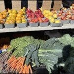 A table full of fresh fruits and vegetables, including apples, oranges, and broccoli.