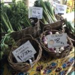 A table full of fresh vegetables, including carrots and turnips, with prices displayed for customers.