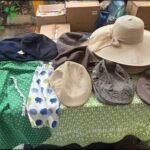 A table full of hats and clothing items, including a brown hat and a blue hat.