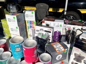 A table full of various items, including a coffee maker and a chair, is set up for a sale.