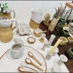 A table full of various items, including a vase, a candle, and a spoon.