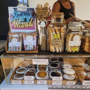 A table full of various pastries and candies, including a jar of fairy wands.