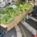 A table full of vegetables, including broccoli, is set up for sale.
