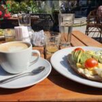 A table with a plate of food, a cup of coffee, and a glass of water.