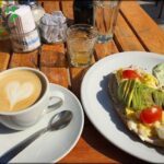 A table with a plate of food, a cup of coffee, and a glass of water.