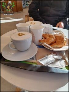 A table with a tray of food and drinks, including a cup of coffee and a pastry.