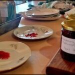 A table with plates of food and a jar of strawberry jam.