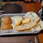 A tray of bread and rolls sits on a table, ready to be eaten.