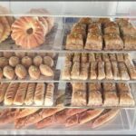 A variety of baked goods, including breads and pastries, are displayed in a glass case, ready to be enjoyed.