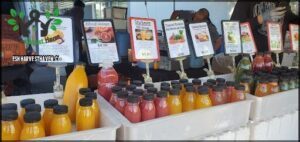 A variety of drinks are displayed at a market, including juices and smoothies.
