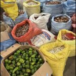 A variety of food items are displayed in a market, including bags of beans, potatoes, and other vegetables.