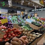 A variety of fresh vegetables are displayed in a market, including tomatoes, potatoes, and broccoli.