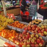 A variety of fruits are displayed at a market, including apples, oranges, and bananas.