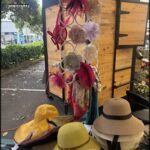 A variety of hats and scarves are hanging on a rack, with a yellow hat and a pink hat being the most prominent.