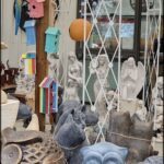A variety of statues and figurines are displayed in a room, including a cat statue and a bird statue.