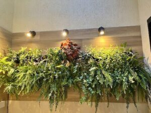 A wall covered in greenery, including a potted plant with a red flower.