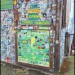 A wall covered in stickers and magnets, with a sign that reads "Open Correo Habitado."