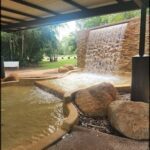 A waterfall in a park with a bench nearby.