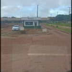 A white car is parked in front of a small building, which is a gas station.