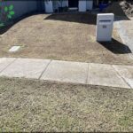 A white mailbox sits in front of a house with a green lawn.