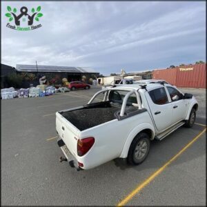 A white pickup truck with a black tray in the back is parked in a lot.