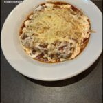 A white plate with a bowl of food on it.