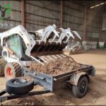 A white tractor with a large blade on the front is parked in a dirt lot.