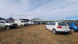 A white van is parked in a field with other cars.