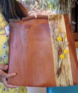 A woman is holding a wooden item with flowers on it.