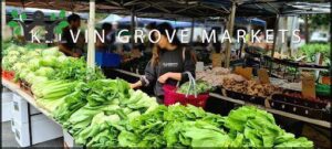 A woman is shopping at a market, holding a basket of vegetables.